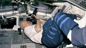 John Glenn se positionne pour prendre des photos, à l’intérieur de la navette Discovery, en 1998.