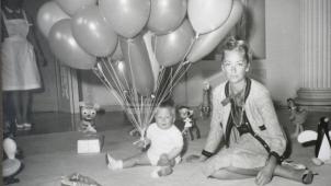 Pour son premier anniversaire, le 15 avril 1961, le prince Philippe pose aux côtés de sa mère Paola parmi les jouets et les ballons qu’il a reçus. © D.R.