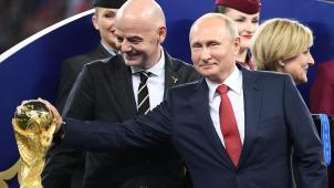 A côté  de Gianni Infantino, président  de la Fifa, Vladimir Poutini touche  la Coupe  du monde avant  la remise  du trophée à la France.