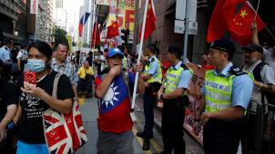 Les deux visages de Hong Kong, à la faveur d’une démonstration de rue
: les manifestants pro-Pékin (à dr.), drapeaux déployés, contenus par la police, répliquent au défilé des militants pro-démocratie.