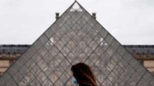 Une femme portant un masque de protection passe devant la pyramide de verre du musée du Louvre fermé dans le cadre des mesures de restriction sanitaire pour lutter contre l