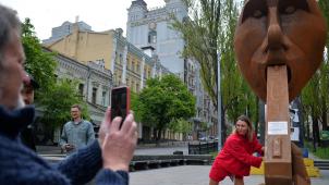 La vie reprend dans la capitale ukrainienne pour le moment épargnée par les frappes russes. Ici, une habitante pose devant l’installation temporaire du sculpteur Dmytro Iv représentant Vladimir Poutine, une arme à feu dans la bouche.