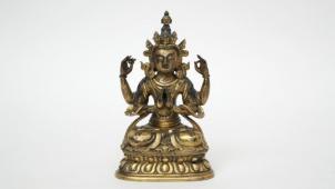 Lot 327. Estimation : 6.000/8.000 €. Chine, Epoque Qianlong (1736-1795). Statue de Divinité à quatre bras en bronze doré représentée assise, sur une double feuille de lotus. Plaque décorée d’un double Vajra. Hauteur : 19 cm.