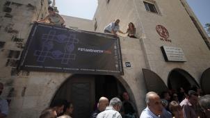 Des activistes accrochent une bannière appelant à la solidarité, après que l’armée israélienne a perquisitionné et fermé tôt jeudi les bureaux de sept ONG palestiniennes.
