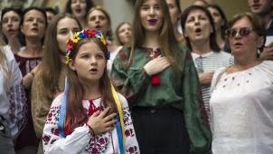 Des réfugiées ukrainiennes chantent l’hymne national sur le seuil de la Maison ukrainienne à Varsovie, en même temps que de nombreux autres Ukrainiens à travers le monde pour tenter d’établir un record et pour protester contre la guerre qui touche leur pays depuis six mois.