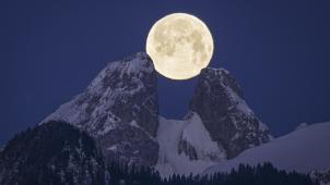 La pleine lune se couche derrière les sommets des Jumelles dans le Chablais Valaisan, en Suisse.