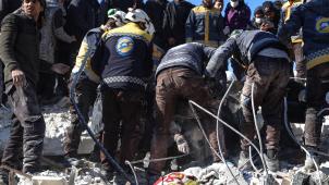 Des secouristes et des habitants dégagent un corps dans les décombres d’un bâtiment du village d’Azmarin aux environs d’Idlib.