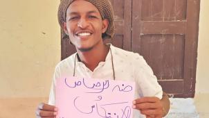 Abodjana Mohmed tien une pancarte disant : « à l’épreuve des balles et des rechutes ». Il a pris cette photo le 6 avril, date du début du sit-in révolutionnaire en 2019 qui a provoqué la chute d’Omar el-Béchir cinq jours plus tard.
