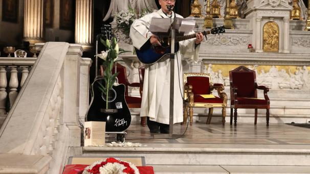 Un prêtre joue de la guitare dans l’église de la Madeleine.