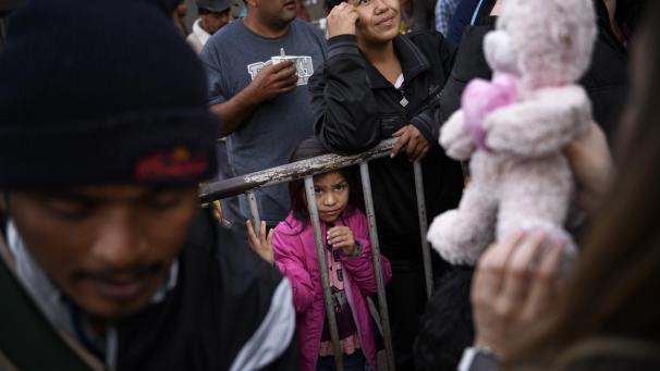 Une jeune fille du Honduras attend de recevoir un cadeau de Noël offert par une organisation non gouvernementale devant un entrepôt vide utilisé comme refuge pour les migrants dans le centre-ville de Tijuana, au Mexique.
