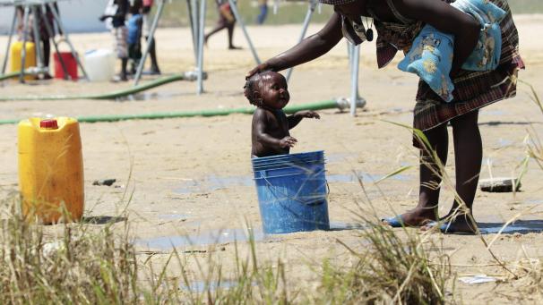 Dans un camp de personnes déplacées suite au cyclone qui a touché le Mozambique, une maman donne le bain à son enfant.