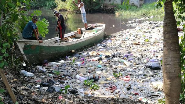 La rivière Loji Pekalongan, en Indonésie, voit ses rives jonchées de déchets. Des hommes tentent de nettoyer la catastrophe.
