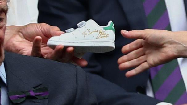Stan Smith en personne remet à Kate Middleton une paire d’Adidas Stan Smith dédicacée pour le prince Louis, lors du championnat de tennis à Wimbledon.