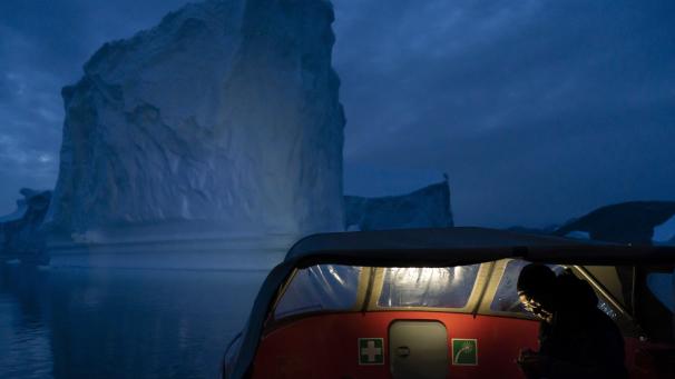 Un bateau navigue, de nuit, près d’un large iceberg of Groenland, alors que l’été 2019 fait fondre de plus en plus de glace.