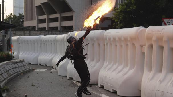 Un manifestant anti-gouvernement lance un cocktail Molotov lors d’une manifestation à Hong Kong. La violence a éclaté à nouveau et des milliers de partisans de la démocratie ont défilé dans le centre-ville au mépris d’une interdiction de police.
