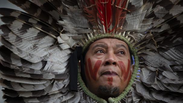 Un dirigeant d’une communauté autochtone du Brésil porte une coiffe en plumes alors qu’il proteste contre la destruction des forêts devant le siège de l’UE à Bruxelles.