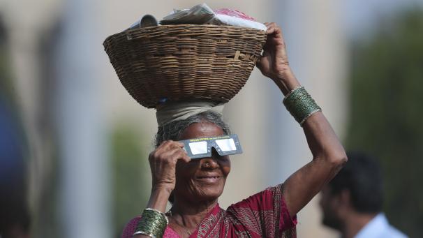 Une vendeuse de rue se munit de lunettes conçues pour les éclipses en Inde.