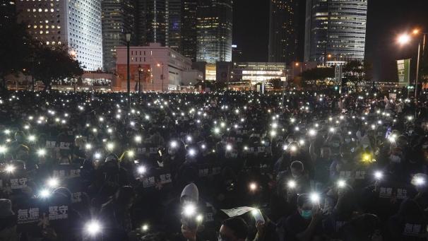 Les manifestants brandissent leur téléphone lors d’un rassemblement organisé par des travailleurs de l’éducation à Hong Kong.