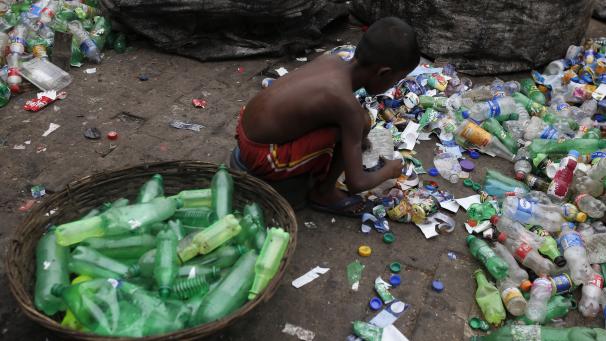Un enfant trie des bouteilles en plastique dans une usine de recyclage à Dhaka au Bangladesh. Tous les jours après l’école, il aide sa grand-mère dans cette usine.