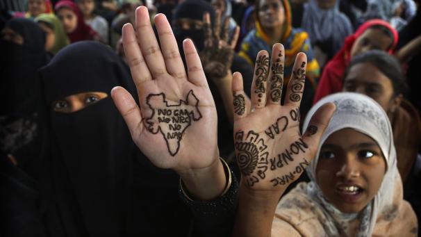 Des femmes et des enfants indiens affichent des slogans au henné sur leurs paumes lors d’une manifestation contre une nouvelle loi sur la citoyenneté à Bangalore, en Inde.