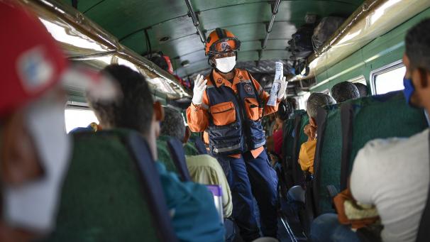 Un membre de l’agence de protection civile vénézuélienne explique les symptômes aux navetteurs et les mesures préventives pour lutter contre le coronavirus à Caracas, au Venezuela.