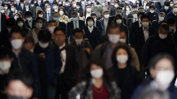 Gare bondée de navetteurs portant un masque durant une heure de pointe à Tokyo au Japon.