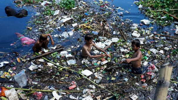 Deux garçons nagent dans des marécages de déchets en Indonésie.