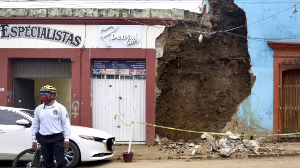 Un policier se dresse devant un building détruit par un tremblement de terre au Mexique.