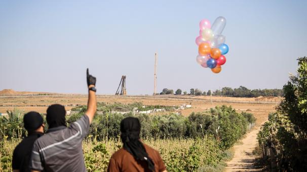 Des Palestiniens masqués lâchent des ballons en direction d’Israël, remplis de produits destinés à détruire par le feu.