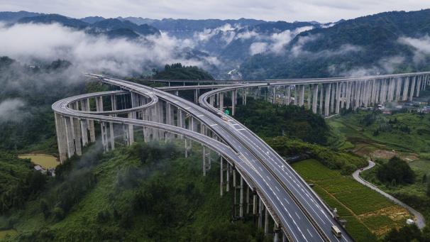Photo aérienne d’une autoroute spectaculaire, qui serpente entre les montagnes et les nuages à Xiangxi Tujia en Chine.