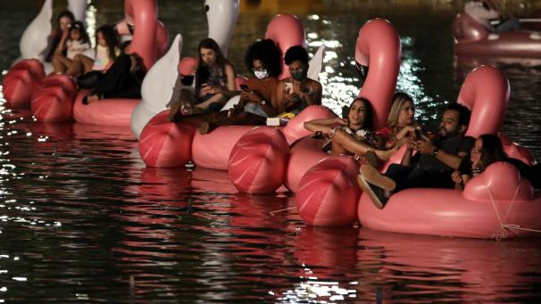 Les gens se prélassent sur des bouées licornes et flamants roses gonflables, sur le lac Sarah Kubstichek, en regardant un film pendant le premier festival flottant à Brasilia, au Brésil.