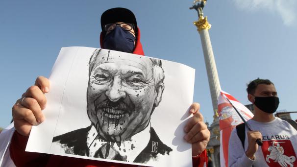 Un manifestant biélorusse tient une pancarte du président décrié Alexander Lukashenko.