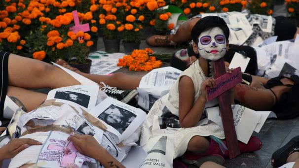 Une jeune fille est entourée de femmes déguisées en « Catrinas » lors d’une représentation pour demander justice aux victimes de féminicides, le Jour des morts à Mexico.