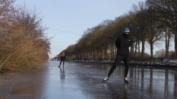 Deux patineurs profitent des joies de la glisse sur un canal gelé près de Nieuweschoot, dans le nord des Pays-Bas.