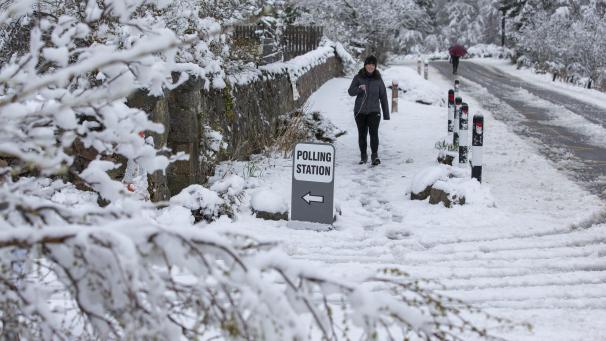 Une femme arrive à un bureau de vote après une importante chute de neige, dans le village de Farr, en Écosse.