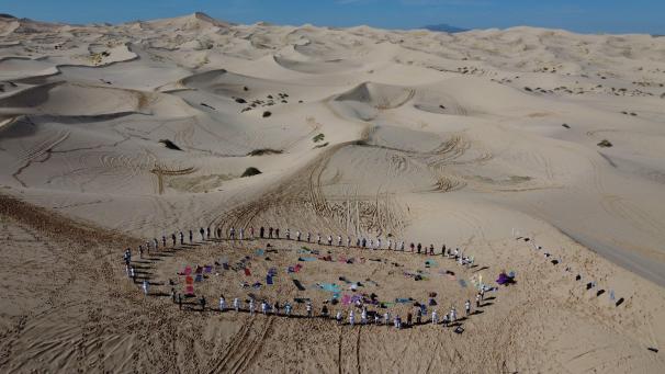 Des gens se tiennent en cercle pour participer à la 6e réunion annuelle de yoga dans les dunes de Samalayuca, au Mexique.