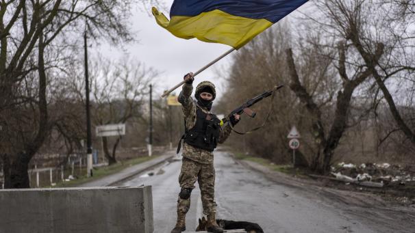 Un soldat ukrainien montre le drapeau à un check-point à Boutcha.