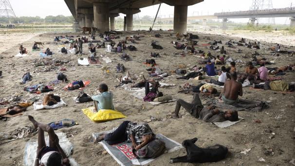 Des sans-abri dorment à l’ombre d’un pont par une chaude journée à New Delhi.