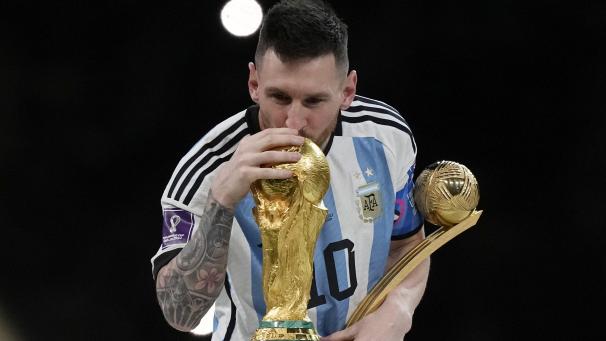 Lionel Messi embrassant le trophée après avoir remporté la finale de la Coupe du monde de football au Qatar, le dimanche 18 décembre 2022.