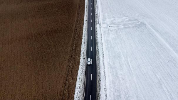Une voiture passe devant un champ enneigé et non enneigé dans la périphérie de Francfort, en Allemagne.
