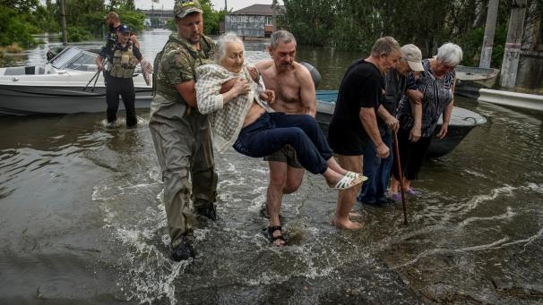 Des personnes évacuent des résidents d’une zone inondée, après la destruction du barrage de Kakhovka.