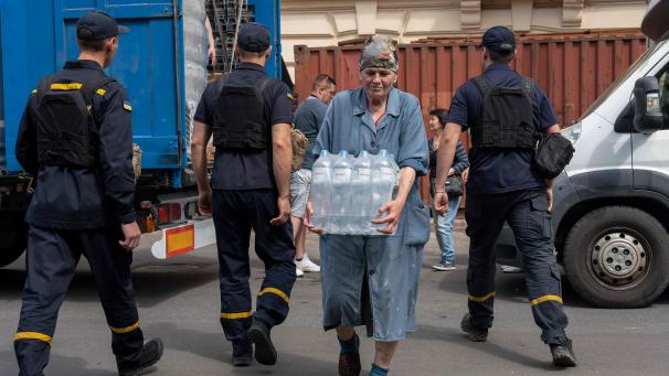 Des sauveteurs et des volontaires déchargent des bouteilles d’eau potable lors de l’évacuation d’une zone inondée à Kherson.