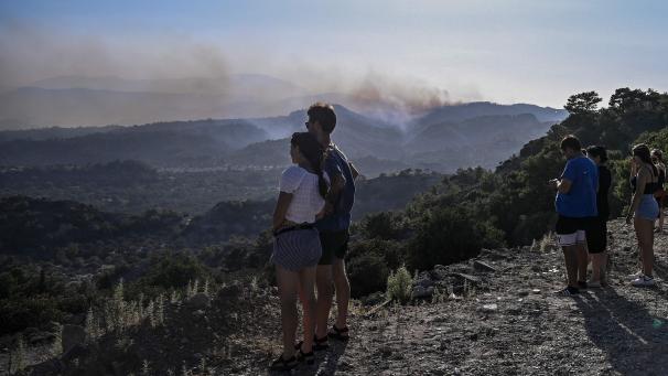 Des habitants évacués des villages de Malonas et Masari se tiennent au sommet d’une colline et observent le feu qui s’approche de leurs villages sur l’île grecque de Rhodes, le 24 juillet 2023.