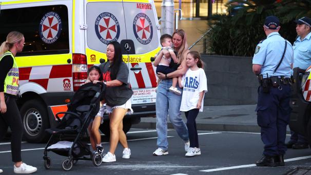 Des familles sortent du centre commercial après une agression à l’arme blanche à Sydney, le 13 avril 2024.