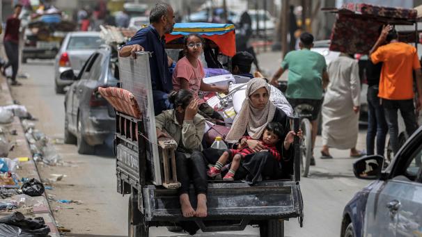 Un homme, une femme et des enfants se trouvent à l’arrière d’un tricycle chargé d’effets personnels alors qu’ils fuient vers Khan Yunis, à Rafah dans le sud de la bande de Gaza.