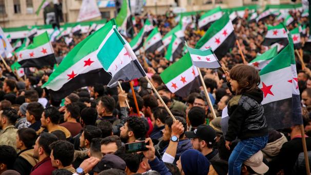 Les participants à une manifestation en mars 2023, à Idlib, en Syrie, brandissent des drapeaux de l’opposition et réaffirment la poursuite de la révolution contre le régime d’el-Assad.
