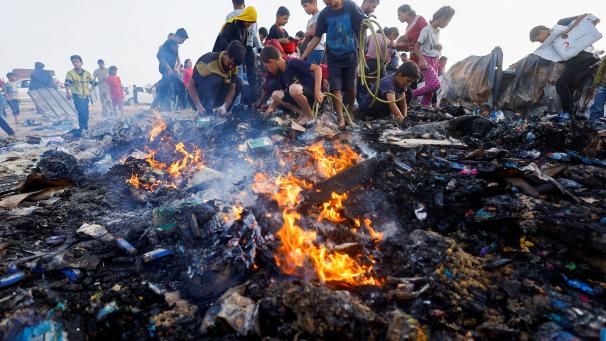 Des enfants palestiniens cherchent des restes de nourriture dans les débris brûlés à Rafah, après l’offensive israélienne sur un camp de déplacés.