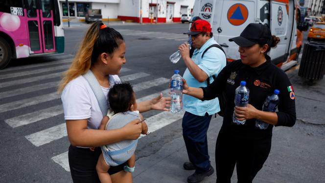 Des membres de la protection civile distribuent des bouteilles d’eau fraîche pendant une vague de chaleur.