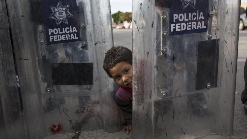 Un jeune migrant de 3 ans, originaire du Honduras, s’amuse entre les boucliers de la police anti-émeutes mexicaine. Le petit garçon fait partie du groupe de migrants issus d’Amérique centrale. Ils demandent à entrer aux États-Unis et marchent pacifiquement.