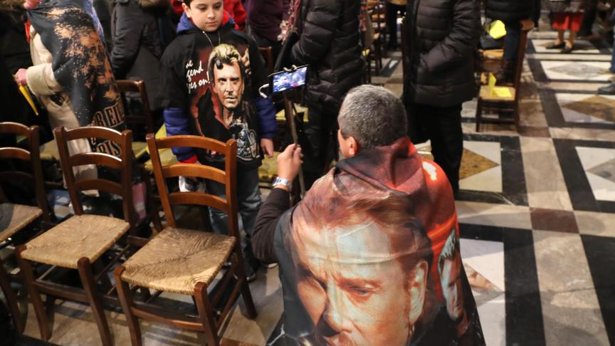 Un fan, affublé d’une cape à l’effigie de Johnny, prend en photo un enfant, lui aussi visiblement fan du Taulier.